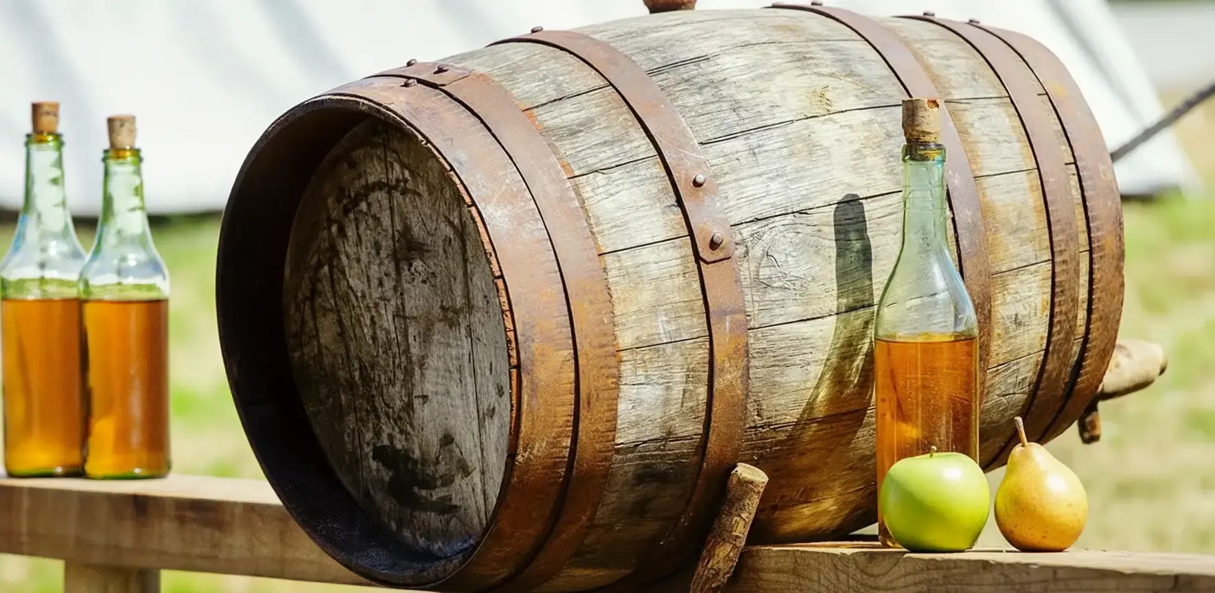 Rustikale Mostverkostung bei MADL auf einem Holzfass mit frischen Äpfeln, Birnen und verschiedenen Mostflaschen im Freien.